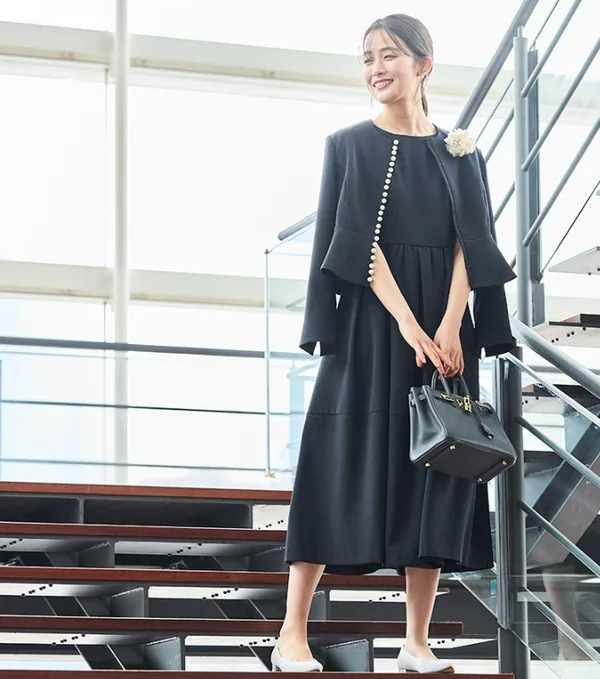 パールボタンが印象的なネイビーのワンピーススーツを着用した女性。卒入学式におすすめの上品なセレモニーコーデ。