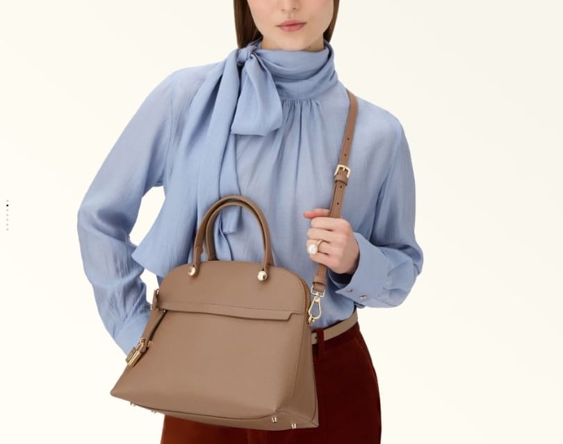 入学式コーデに合わせやすいベージュのブランドバッグを持つ40代女性
