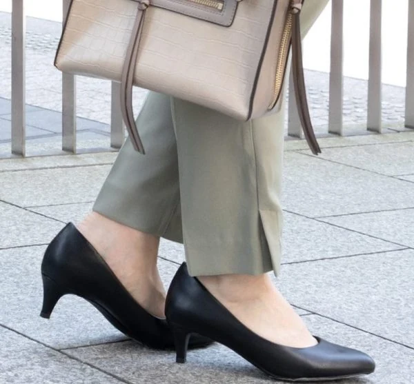グレージュのパンツに黒のローヒールパンプスを合わせた女性の足元。シンプルなプレーンパンプスの着用写真。