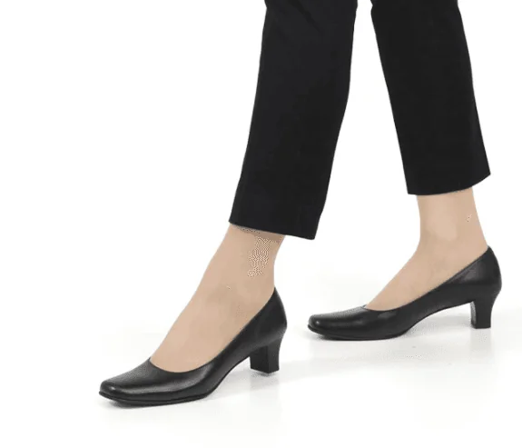 黒のアンクル丈パンツにシンプルな黒のミドルヒールパンプスを合わせた女性の足元。低めの安定感のあるヒールが特徴。