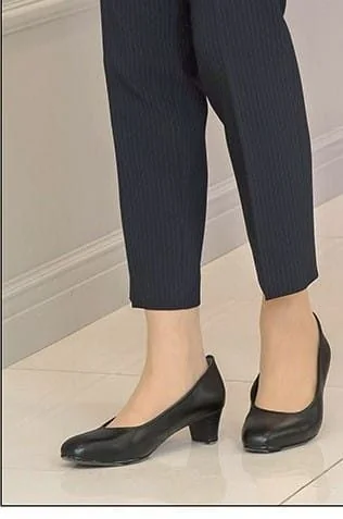 ネイビーのパンツスーツに黒のローヒールパンプスを合わせた女性の足元。丸みのあるつま先と太めの低いヒールが特徴。