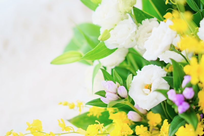 白と黄色の花が飾られた明るいお供えの花束