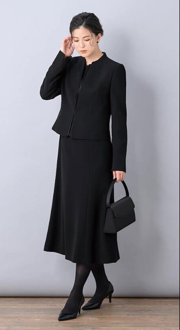 黒のロング丈アンサンブルスーツを着た女性