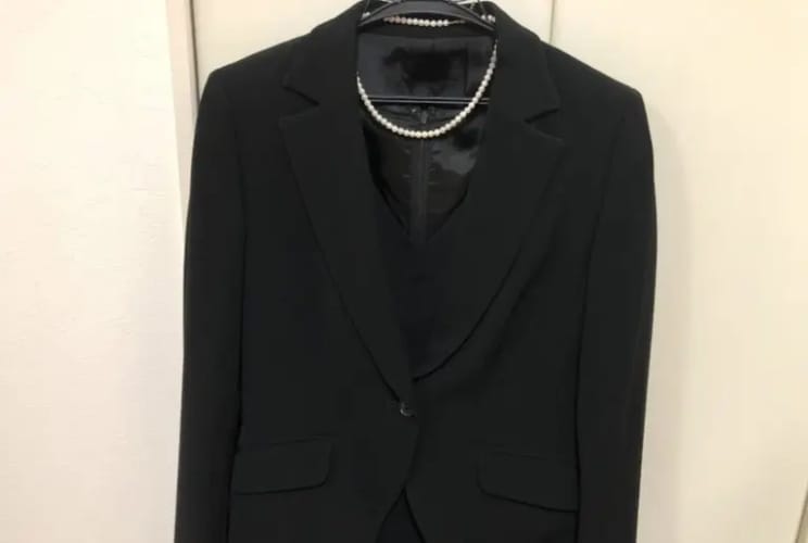 クローゼットにかけた黒の喪服スーツとパールネックレス｜喪服の保管イメージ