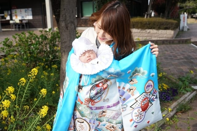 お宮参りで祝い着を着た赤ちゃんを抱く母親