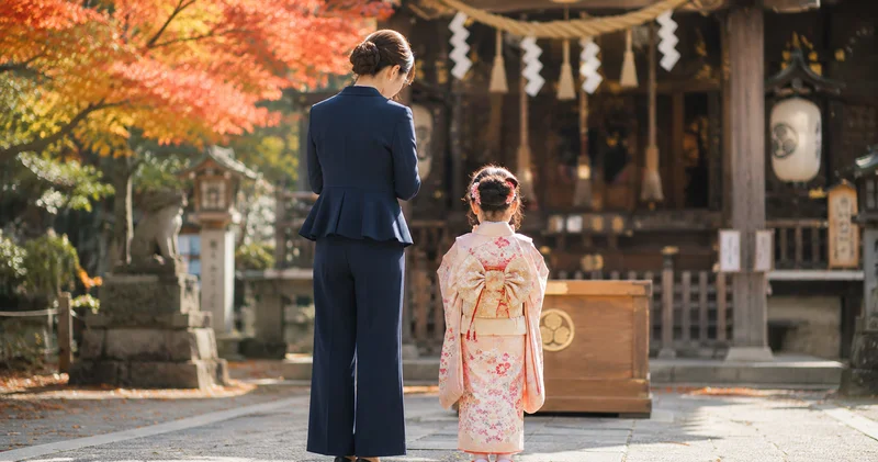 七五三の参拝でパンツスーツを着た母親が子どもと並んでお参りする後ろ姿