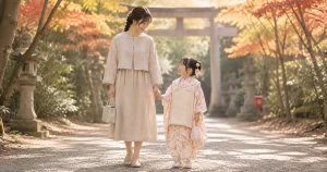 七五三の境内で自然素材のジャケット×ワンピースを着た母親が子どもと歩いている様子