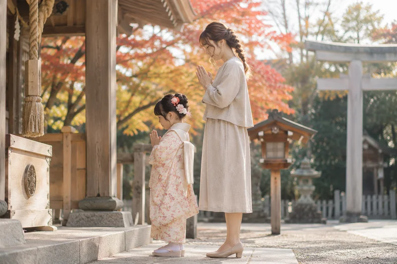 七五三の神社で自然素材のワンピーススーツを着た母親が子どもと参拝する様子