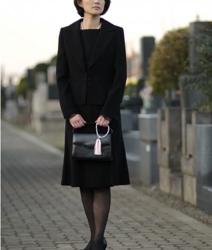 お墓の前で喪服を着た女性