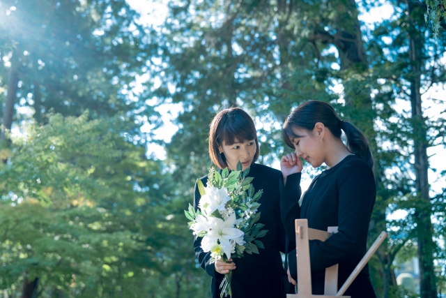 お葬式で白い花を持ち、遺族を気遣う女性