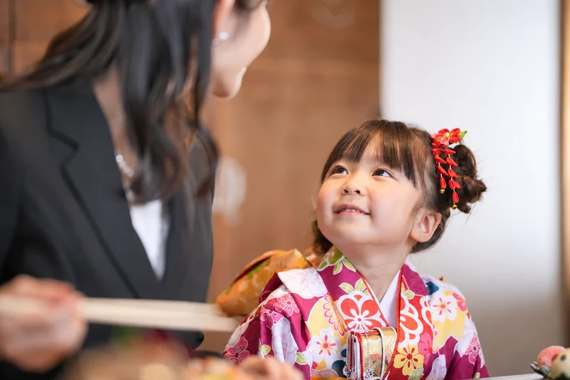 母親を見上げて笑う着物姿の七五三の女の子
