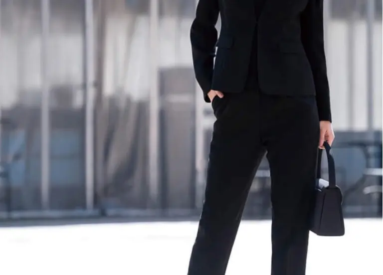 黒のパンツスーツと黒ハンドバッグを持つ女性の下半身｜仕事帰りのお通夜参列スタイル