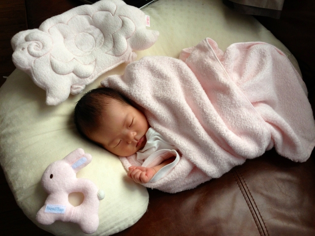 ピンクのブランケットに包まれて眠る赤ちゃん。お宮参りやセレモニー前のイメージカット。