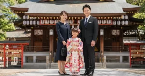 千歳飴を持って神社にお参りする七五三の家族