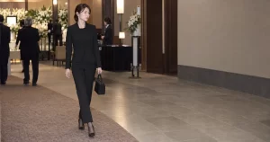 喪服のパンツスーツを着た30代女性が斎場を歩く様子