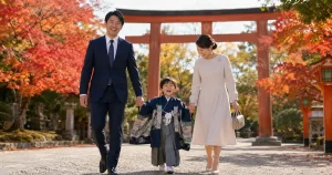 七五三の父親の服装｜ネイビースーツのパパと着物姿の子ども、フォーマルワンピースのママが神社を歩く家族写真