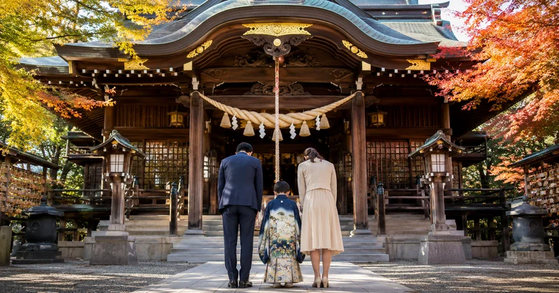 七五三の参拝で拝殿の前に並び手を合わせるネイビースーツの父親と晴れ着の子ども、母親の後ろ姿